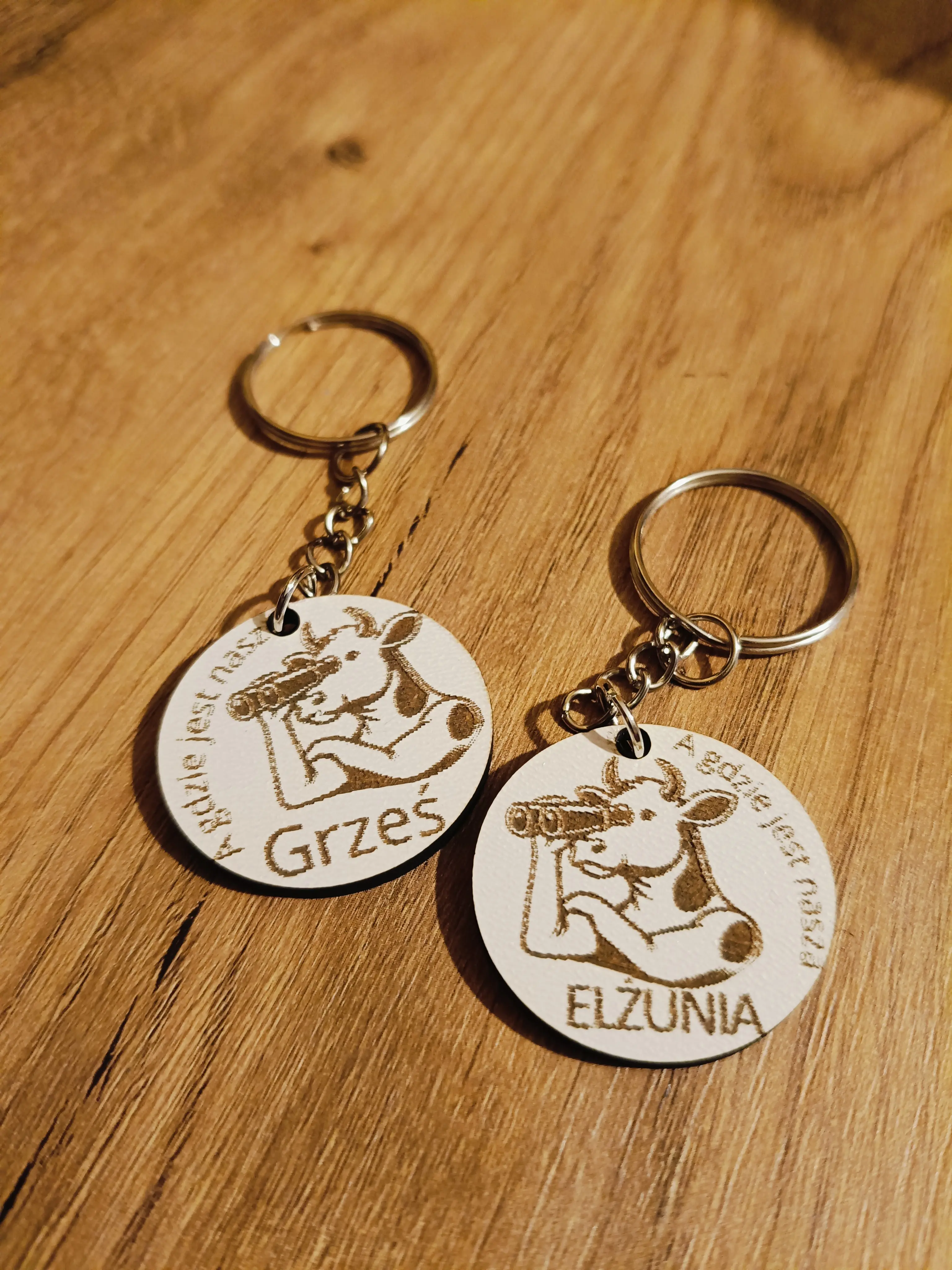 Drewniane breloki z grawerem krowy z lornetką i napisami A gdzie jest nasz Grześ oraz A gdzie jest nasza Elzunia