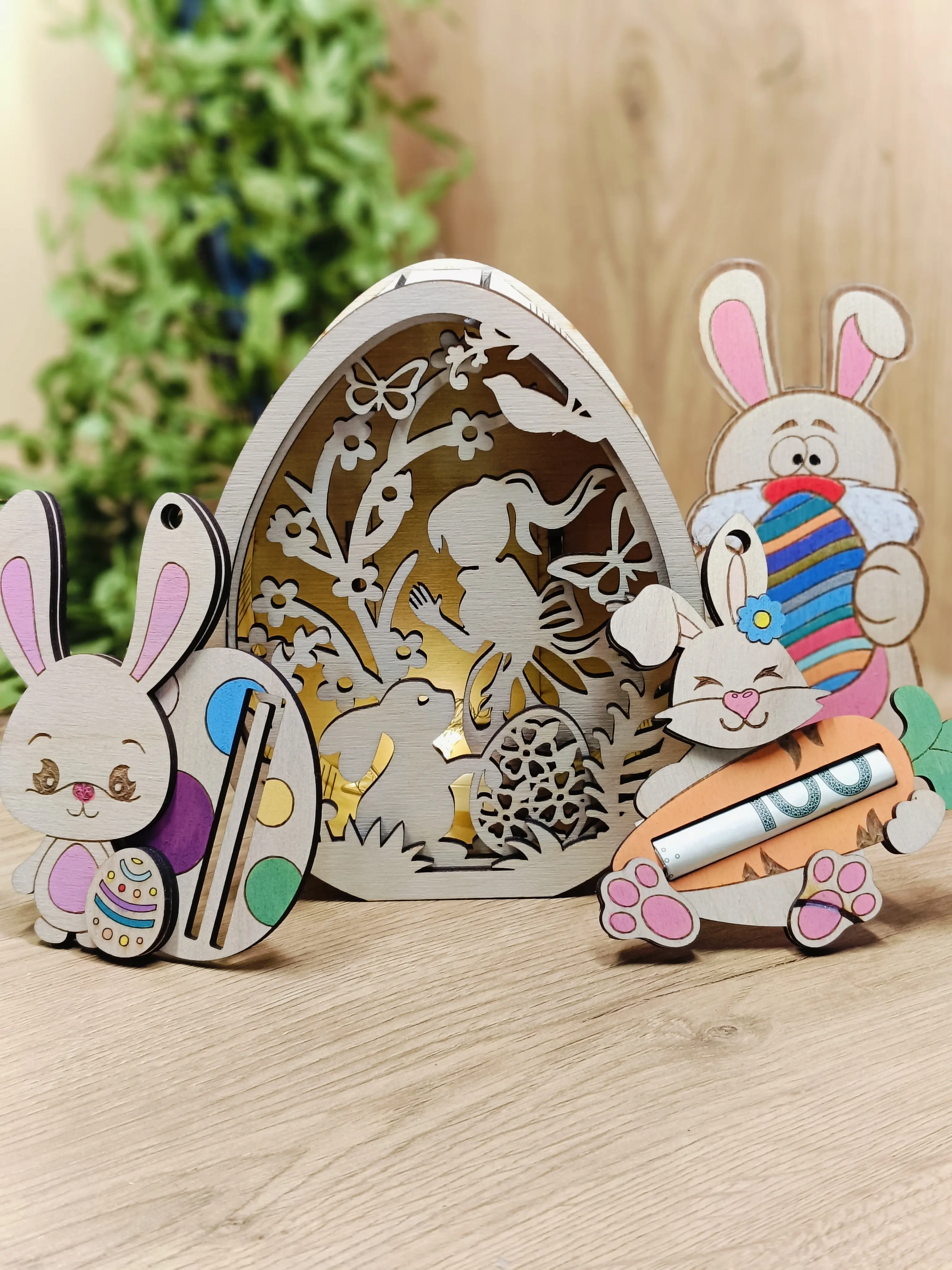 Drewniana dekoracja wielkanocna z podświetlanym ażurowym jajkiem z motywem wróżki, kwiatów i królików oraz figurkami dwóch króliczków i kotka