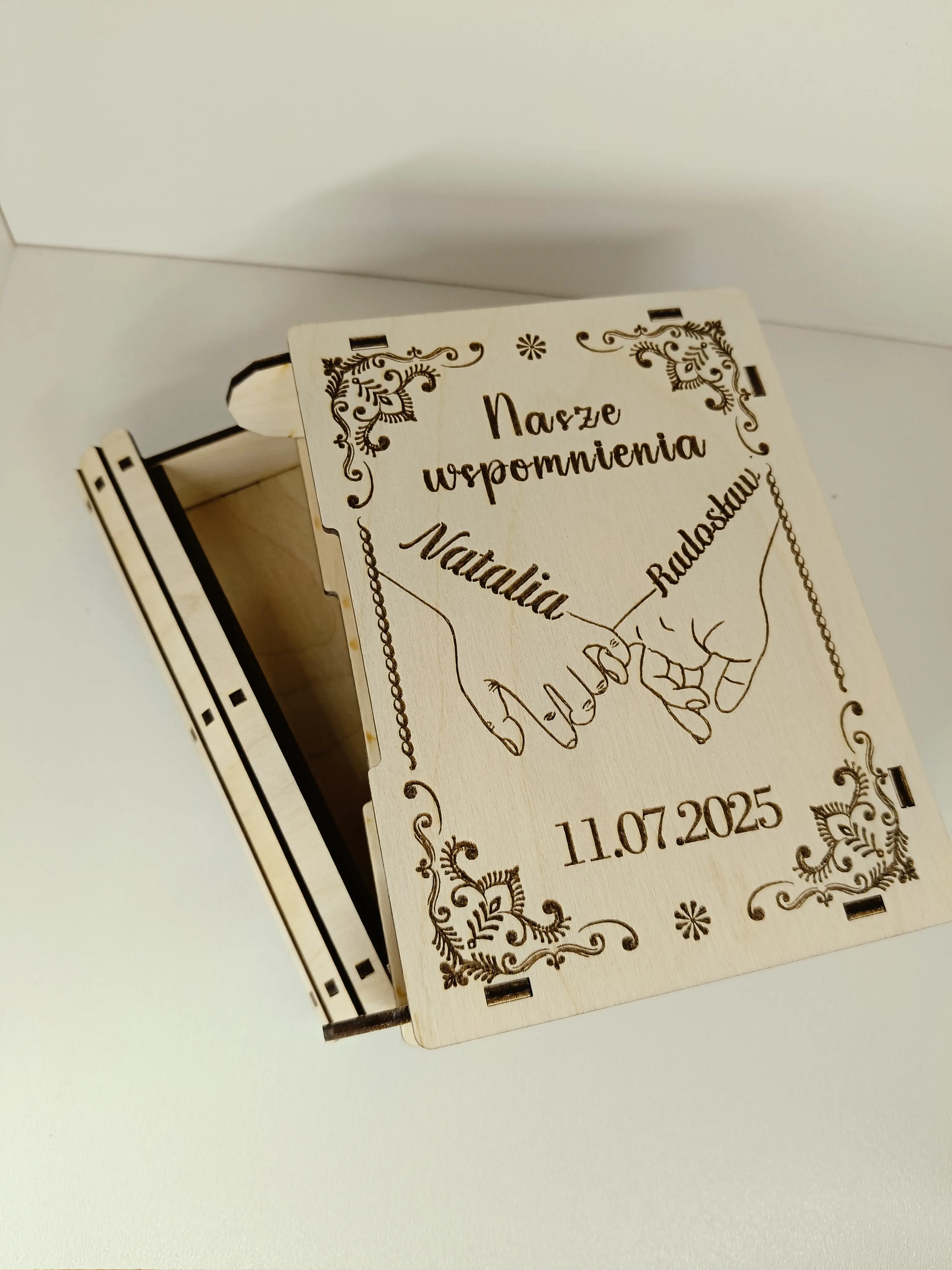 Drewniane pudełko wspomnień z grawerem Nasze wspomnienia, imionami Natalia & Radosław, datą 11.07.2025 oraz motywem splecionych dłoni i kwiatowym ornamentem