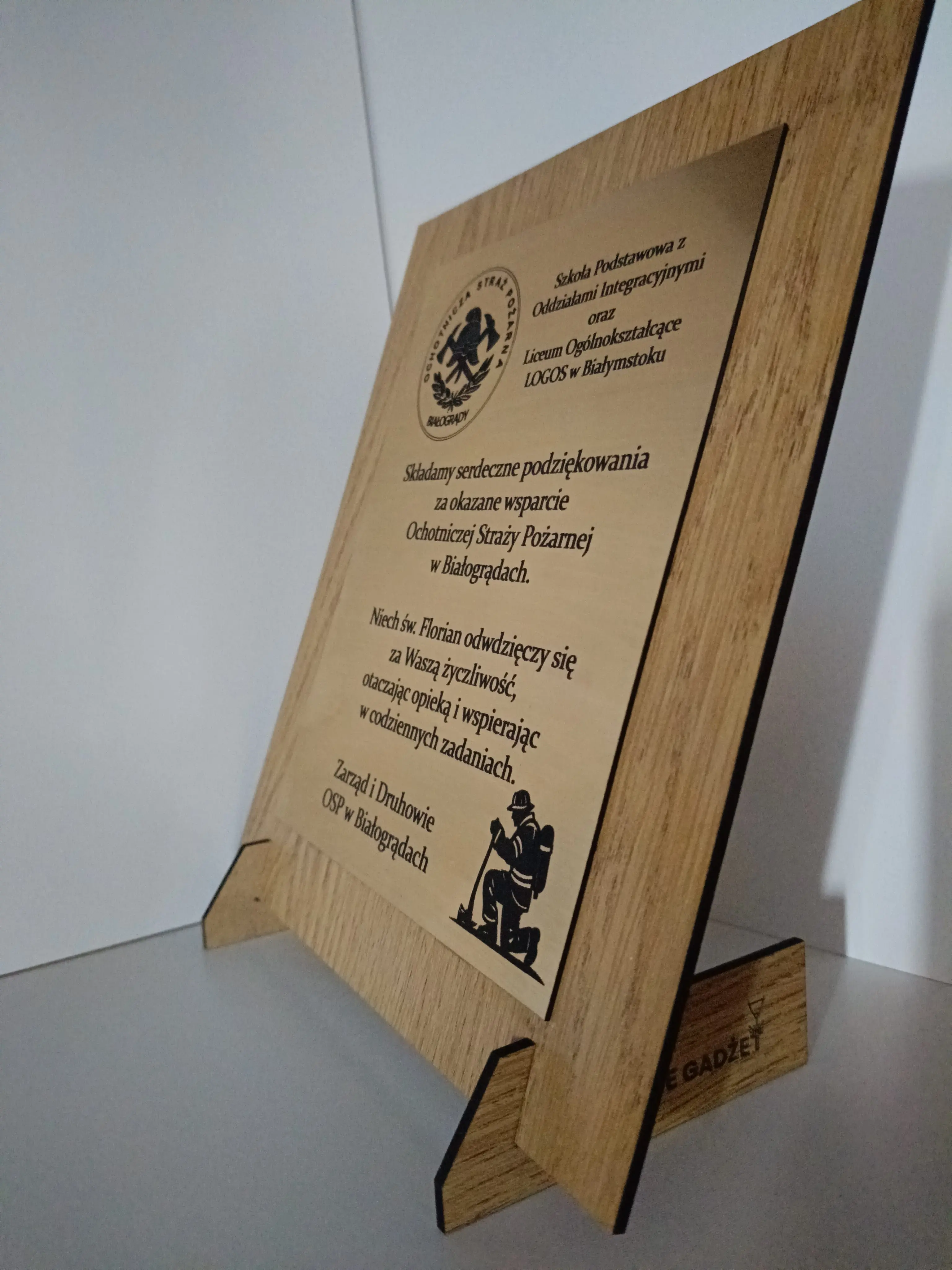Drewniana tablica pamiątkowa na stojaku z grawerem i logotypem OSP Białogrądy